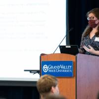 Scholar wearing mask giving oral presentation.
